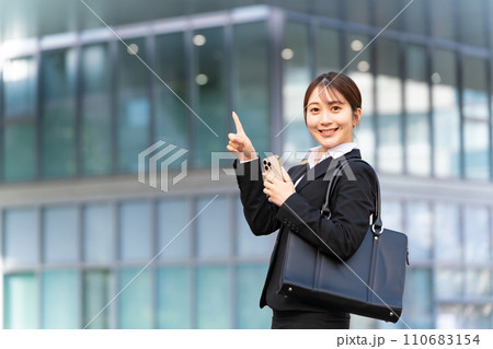 スマホを持って指を差すビジネススーツの若い女性 スマホを持って指を差すビジネススーツの若い女性 110683154