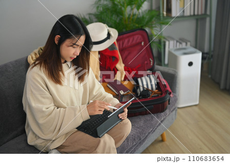 Happy young woman reading tourist blog online or booking tickets or hotel room on laptop Happy young woman reading tourist blog online or booking tickets or hotel room on laptop 110683654