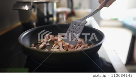Chef stir ham or bacon slices on hot pan, person frying meat for breakfast or dinner Chef stir ham or bacon slices on hot pan, person frying meat for breakfast or dinner 110684145