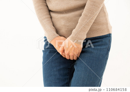 股間を押さえるミドル女性 110684158