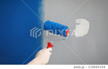 Worker with roller tool ready to paint walls, cover in blue colour 110684164