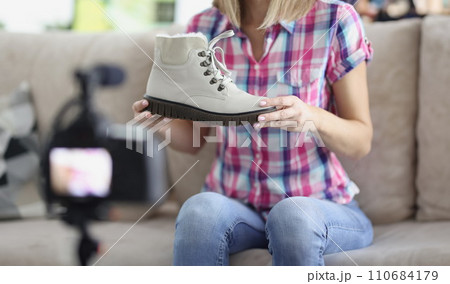 Woman present trendy white boot showing on camera, try to sell online 110684179