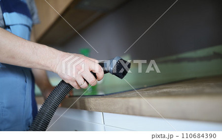 Male worker remove dust with vacuum cleaner, nozzle on cleaning device Male worker remove dust with vacuum cleaner, nozzle on cleaning device 110684390