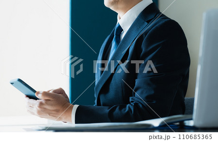 スマホでメールを送るビジネスマンの手元 110685365