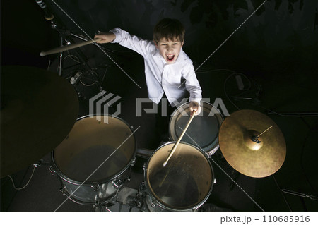 The child plays the drums. Boy musician behind a drum kit. The child plays the drums. Boy musician behind a drum kit. 110685916