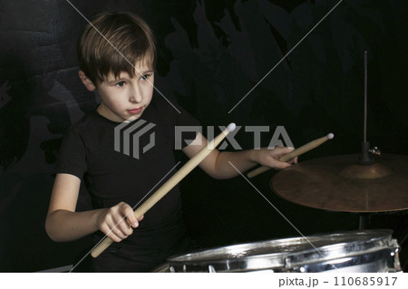 The child behind the drum. A boy with drumsticks behind a drum kit. The child behind the drum. A boy with drumsticks behind a drum kit. 110685917