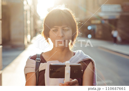 A girl in the city films herself on her phone 110687661