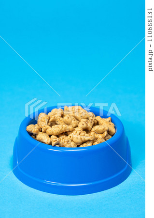 A treat for cats and kittens is a fish-shaped catnip cookie in a blue bowl, copy space for text. 110688131