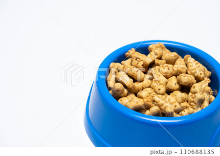 A treat for cats and kittens is a fish-shaped catnip cookie in a blue bowl, copy space for text. A treat for cats and kittens is a fish-shaped catnip cookie in a blue bowl, copy space for text. 110688135