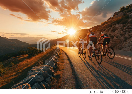 Cyclists team rides on mountain road at sunset sky. Cyclists team rides on mountain road at sunset sky. 110688802