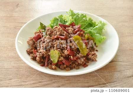 spicy fried chop beef meat couple dry chili with lettuce on plate 110689001
