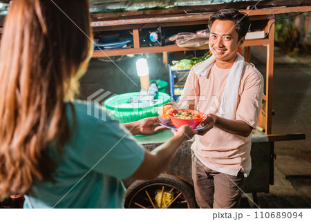 male seller serving bowl of noodle to customer 110689094