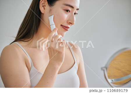 電気シェーバーで顔を剃る30代女性 110689179