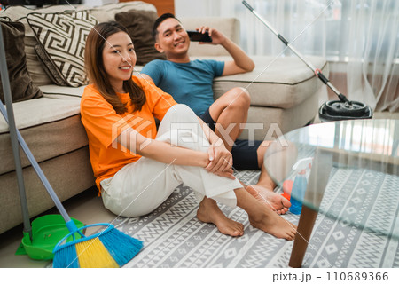 asian couple sitting on rug after housekeeping asian couple sitting on rug after housekeeping 110689366