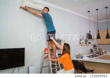 asian woman helping partner fixing airconditioner 110689563