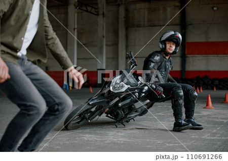 Instructor explaining student motorcyclist his mistake at training class Instructor explaining student motorcyclist his mistake at training class 110691266