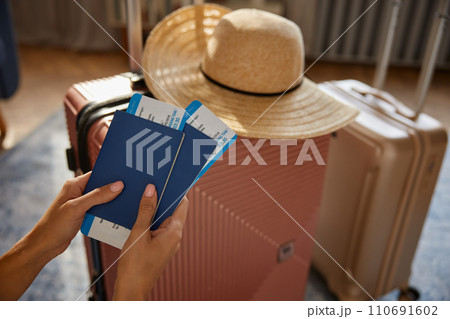 Female holding passport and ticket with boarding pass over packed luggage bags 110691602