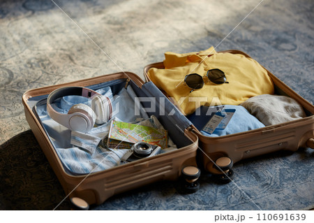 Suitcase packed with clothes, hat and personal belongings for travel Suitcase packed with clothes, hat and personal belongings for travel 110691639