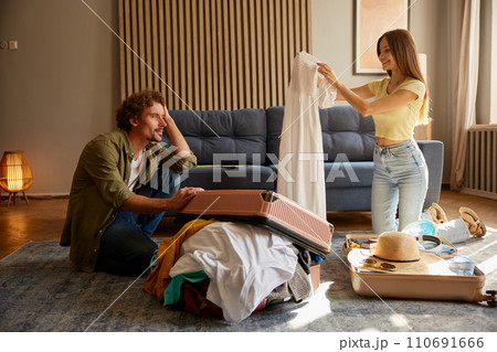 Young romantic couple preparing luggage for trip at home living room Young romantic couple preparing luggage for trip at home living room 110691666