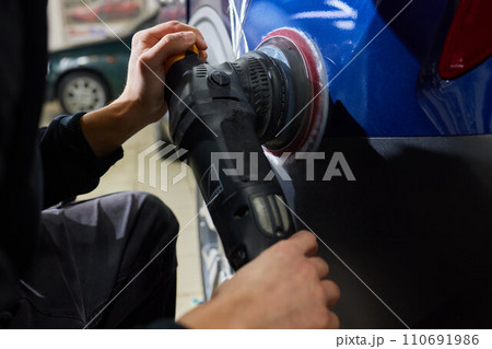 Man with an orbital polisher in car workshop polishing car closeup Man with an orbital polisher in car workshop polishing car closeup 110691986