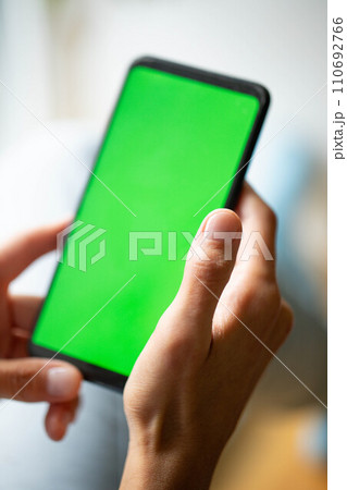 Black smartphone with green screen mock up in female hands close up. Chroma key. Soft focus. Black smartphone with green screen mock up in female hands close up. Chroma key. Soft focus. 110692766