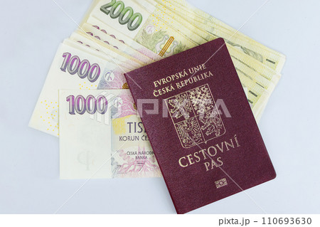 Passports of Czech Republic are stacked on white background with various denominations of CZK koruna banknotes 110693630