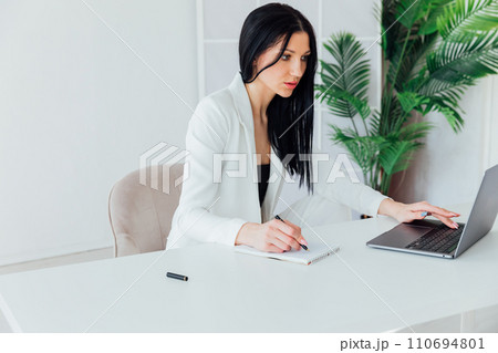 Woman in white business suit working on laptop small business online office 110694801