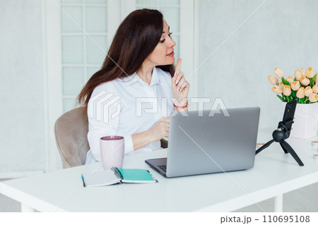 Beautiful brunette woman negotiating on laptop business online in office Beautiful brunette woman negotiating on laptop business online in office 110695108