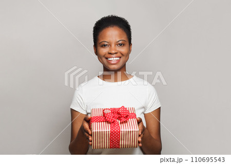 Cheerful happy young woman with gift present box standing on white background Cheerful happy young woman with gift present box standing on white background 110695543
