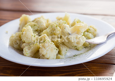 Cooked cauliflower, steamed, in a plate with spices . Cooked cauliflower, steamed, in a plate with spices . 110695924