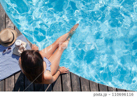 Woman on wooden deck near swimming pool 110696116