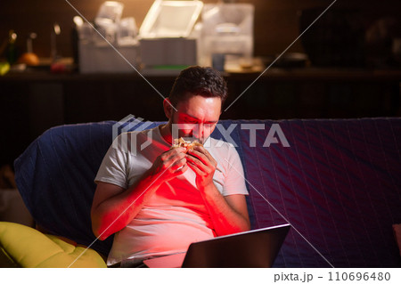 a young man, wearing latex gloves, preparing a falafel sandwich in a pita bread, with chopped tomato and onion a young man, wearing latex gloves, preparing a falafel sandwich in a pita bread, with chopped tomato and onion 110696480