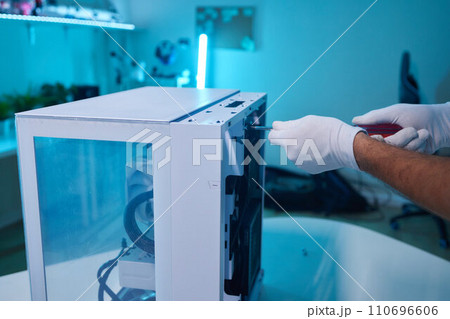 Rear view of a young man installing graphics card to his desktop computer at home. Rear view of a young man installing graphics card to his desktop computer at home. 110696606