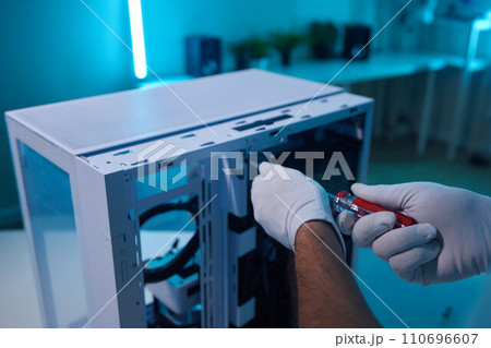 Rear view of a young man installing graphics card to his desktop computer at home. 110696607