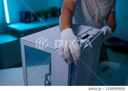 Rear view of a young man installing graphics card to his desktop computer at home. 110696608