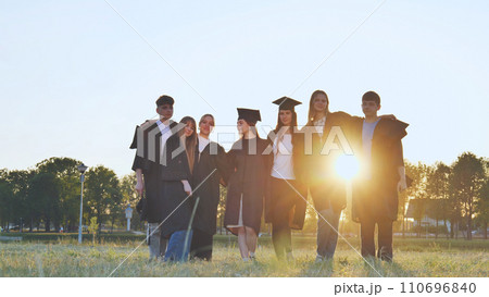 Student alumni waving at sunset. 110696840