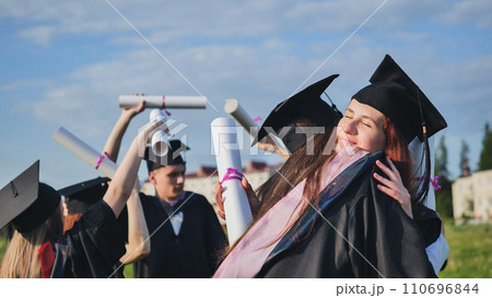 Two college graduates girls hugging on a sunny day. 110696844