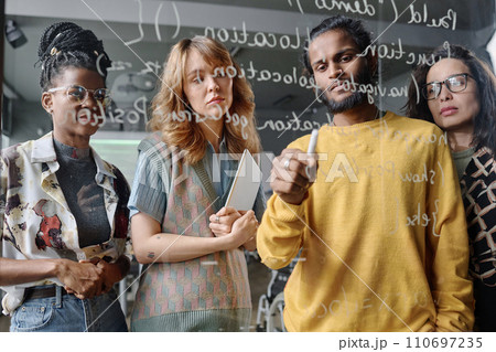 Young pensive programmers working in team on code written on glass wall in office 110697235