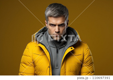Angry man in a yellow winter jacket on a yellow background 110697391