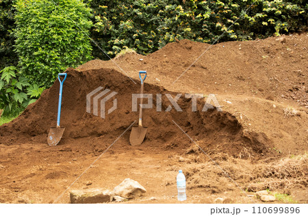 two shovels stand near large pile of earth. diggers break 110699896