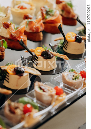 Assortment of delicious snacks on the open buffet festive table in restaurant. Catering plate 110700208