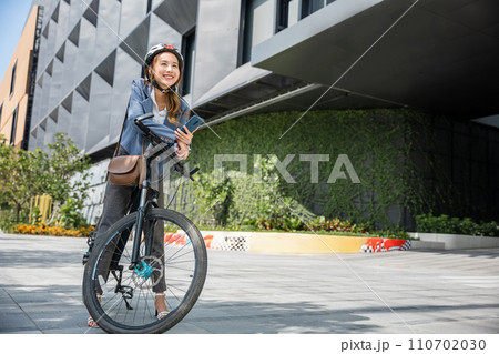 Eco friendly, Lifestyle business female using bike outdoor in morning, Asian smiling young woman with helmet hold mobile smart phone talk with business during go to office work at street with bicycle Eco friendly, Lifestyle business female using bike outdoor in morning, Asian smiling young woman with helmet hold mobile smart phone talk with business during go to office work at street with bicycle 110702030