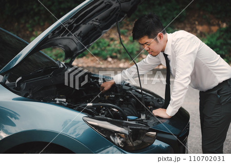 Asian businessman car broken breakdown, angry young stressed man stands trouble car failure problem looking in frustration at failed engine in morning, accident on road outdoor, late for business work Asian businessman car broken breakdown, angry young stressed man stands trouble car failure problem looking in frustration at failed engine in morning, accident on road outdoor, late for business work 110702031