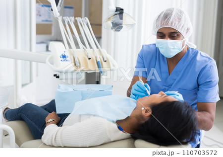Male dentist treating female patient in dental clinic 110703572