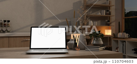 A white-screen laptop computer on a kitchen island in a modern kitchen at night. 110704603