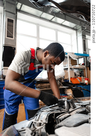Young African male mechanic repairs car in garage close up Young African male mechanic repairs car in garage close up 110710722