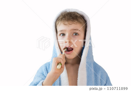 small child, boy in a blue terry robe with a toothbrush on white. A child brushes his teeth. Healthcare and dental care small child, boy in a blue terry robe with a toothbrush on white. A child brushes his teeth. Healthcare and dental care 110711899