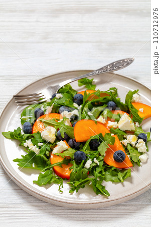 arugula persimmon cheese berries salad, top view arugula persimmon cheese berries salad, top view 110712976