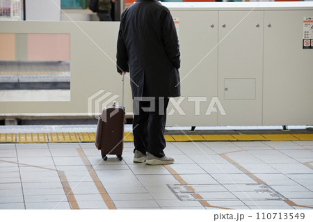 冬の名古屋駅のホームでスーツケースを持って電車待ちのシニア男性の姿 110713549
