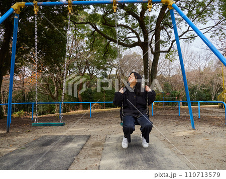 冬の公園で楽しくブランコを遊んでいる子供の様子 110713579